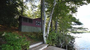 Een houten chalet met terras en uitzicht op een meer.