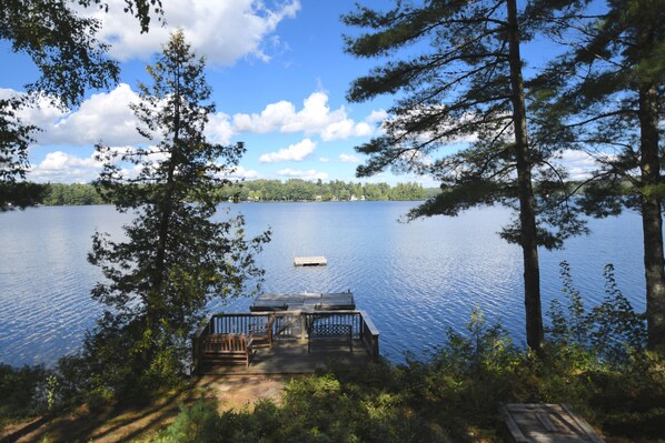 A wooden dock extending into a calm lake surrounded by trees.