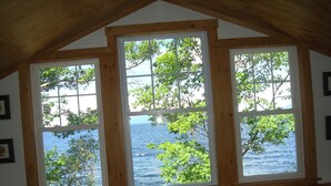 Ein Zimmer mit Blick auf das Meer durch drei Fenster mit Holzzargen.