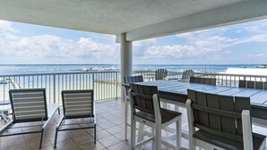 Un patio techado al aire libre con vista al océano, que incluye una mesa y sillas.