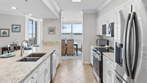 Una cocina moderna con armarios blancos, electrodomésticos de acero inoxidable y una isla grande con un fregadero.