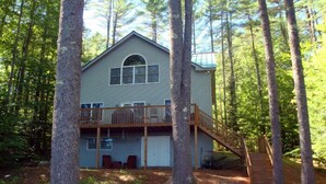 Une cabane à deux étages dotée d’une terrasse en bois et d’un escalier menant à l’étage supérieur.
