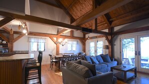 Un vaste espace de vie doté d’un plafond en bois, d’un canapé, d’une table basse et d’un coin repas avec une table et des chaises.