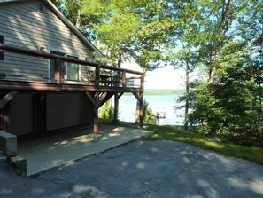 A cabin with a deck overlooking a lake, surrounded by trees.