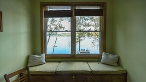 A corner window seat with a view of a lake and dock. - Spacious, cozy waterfront cottage on Norway Lake with hiking trails nearby. (Norway)