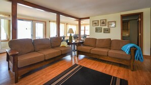 A spacious living room with a large sectional sofa, a coffee table, and a dining area with chairs. - Spacious, cozy waterfront cottage on Norway Lake with hiking trails nearby. (Norway)