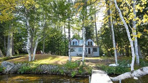 A lakeside cabin with a dock, surrounded by birch trees and a stone wall. - Spacious, cozy waterfront cottage on Norway Lake with hiking trails nearby. (Norway)