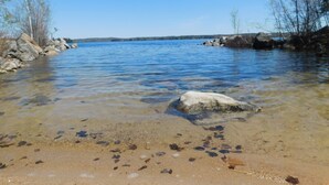 A clear lake with visible rocks and pebbles at the shore.