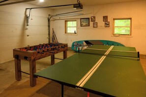 A room with a foosball table, ping pong table, and a pool table.