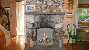 Ein Steinkamin mit Kaminabdeckung, ein Besen, Kerzen und eine Blumenvase.
