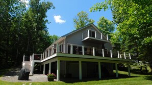 A two-story house with a balcony, surrounded by trees and a well-maintained lawn.