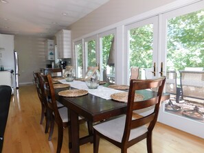 A dining area with a wooden table, woven placemats, and chairs. - Beautiful home on Sebago Lake Basin with expansive yard and sandy beach! (Standish)
