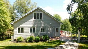 A two-story house with a front porch, a small garden, and a paved driveway.