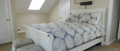 Un dormitorio con cama, dos lámparas de noche, ventilador de techo y tragaluz.