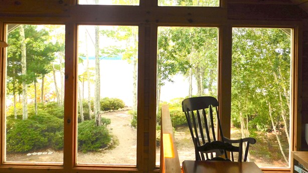 A room with large windows offering a view of a forested area.