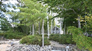 A cabin surrounded by a rocky landscape and dense greenery.