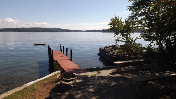 A lakeside dock with a picnic table and a fire pit. - Cozy cottage on Sebago Lake with amazing views and excellent swimming! (Raymond)
