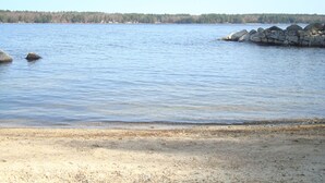 A calm lake with a rocky shoreline and a forest in the background. - Cozy cottage on Sebago Lake with amazing views and excellent swimming! (Raymond)