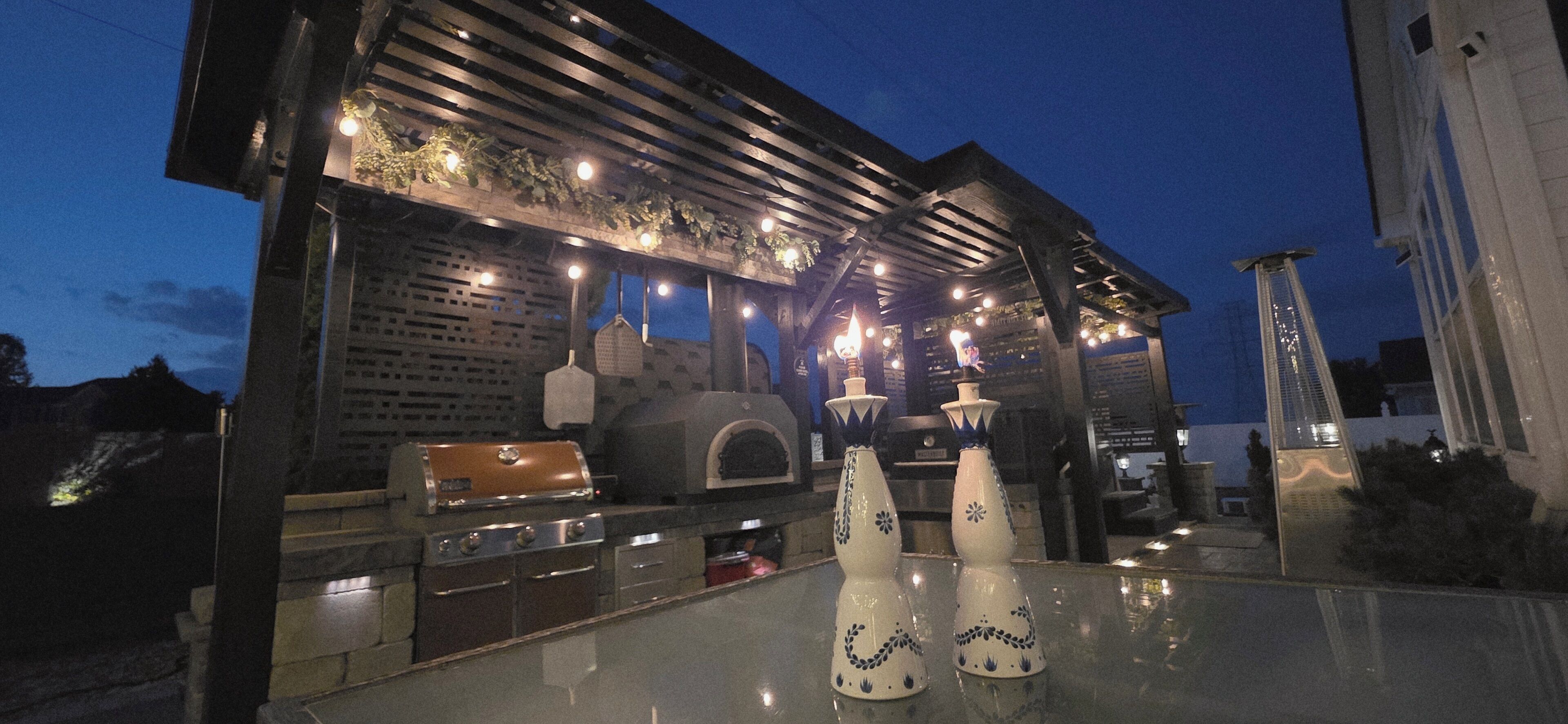 Een buitenkeuken met een grill, oven en decoratieve vazen.