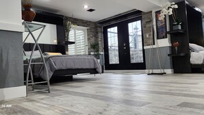 Un dormitorio moderno con una cama, una escalera, una planta en maceta y un ventanal grande.