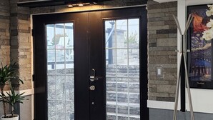 Un interior moderno con una puerta negra, pared de piedra y una lámpara de pie.