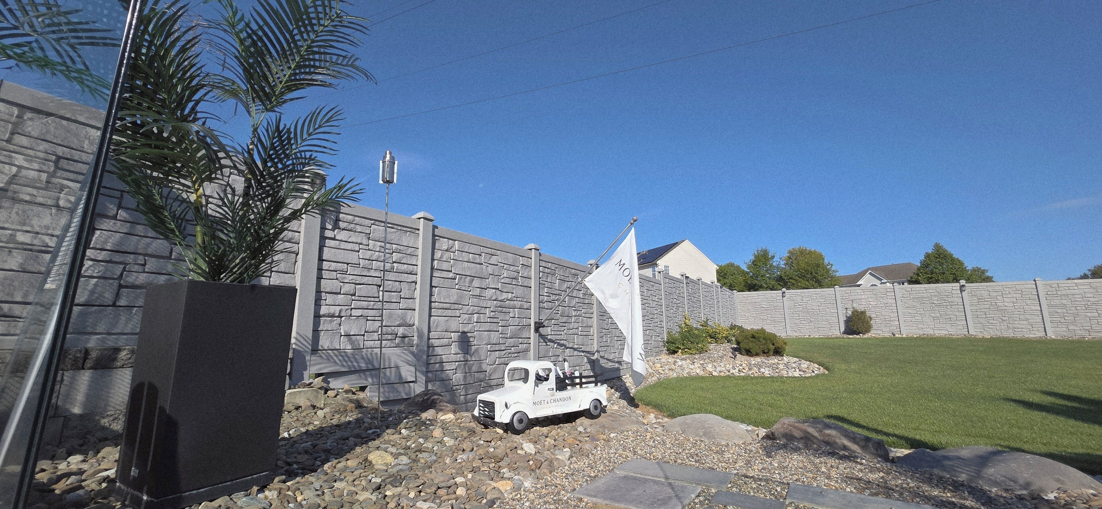 A residential area with a stone wall, a parked truck, and a lawn.