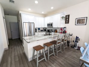 Una cocina moderna con armarios blancos, electrodomésticos de acero inoxidable y encimera de mármol.