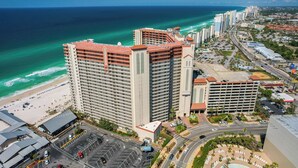Un hôtel de grande hauteur, avec de nombreux étages, un parking et une vue sur la plage.