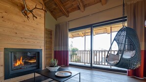 A modern living room with a fireplace, a hanging chair, and a large window with a view.
