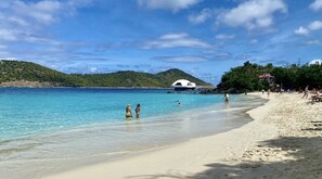 A beach with clear turquoise water, a sandy shore, and a white building with a dome roof near the water's edge. - NEW! Remodeled studio just Steps from Beach, Pool, and Restaurants! (St Thomas)