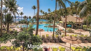 Ein Resort mit Poolbereich, umgeben von Palmen und Liegestühlen.