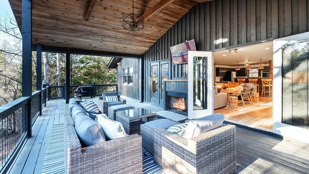 Een overdekt terras met rieten meubilair en een open haard.