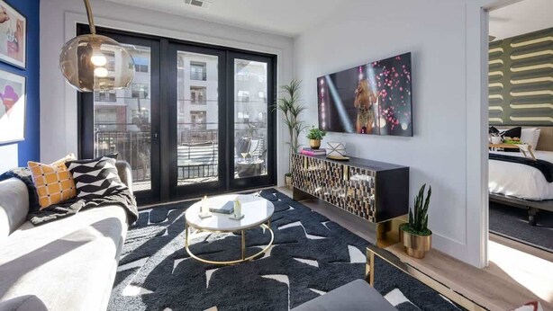 Ein modernes Wohnzimmer mit Sofa, Couchtisch und einem großen Fenster mit Blick auf Gebäude.