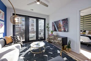 Ein modernes Wohnzimmer mit Sofa, Couchtisch und einem großen Fenster mit Blick auf Gebäude.