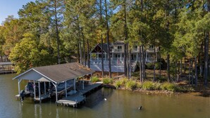 Un chalet au bord du lac, doté d’un quai, entouré de grands pins.
