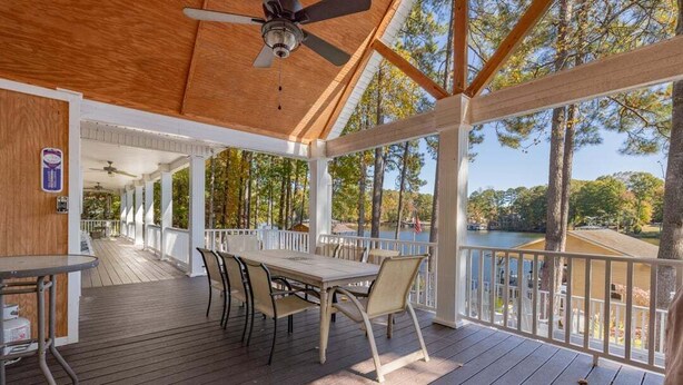 Une terrasse couverte, dotée d’une table et de chaises, qui offre une vue sur un plan d’eau et des arbres.
