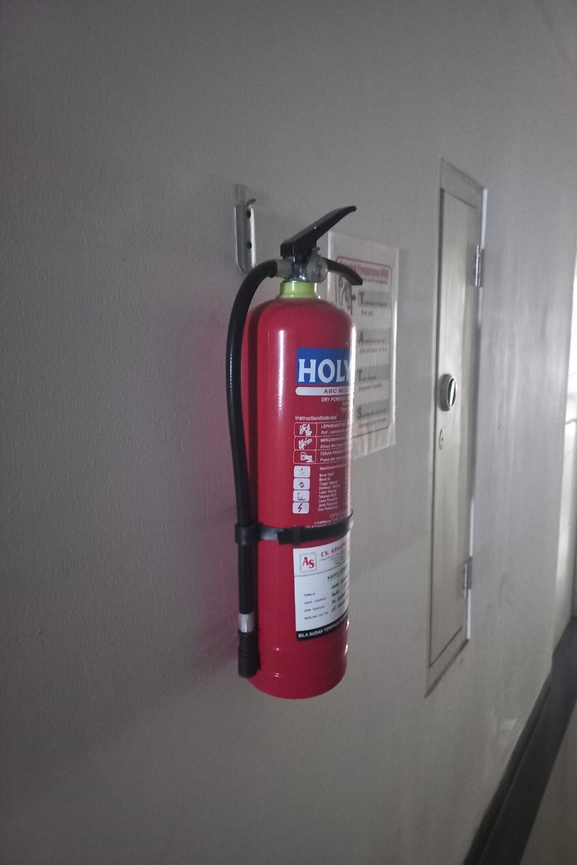 A red fire extinguisher mounted on a wall in a hallway.