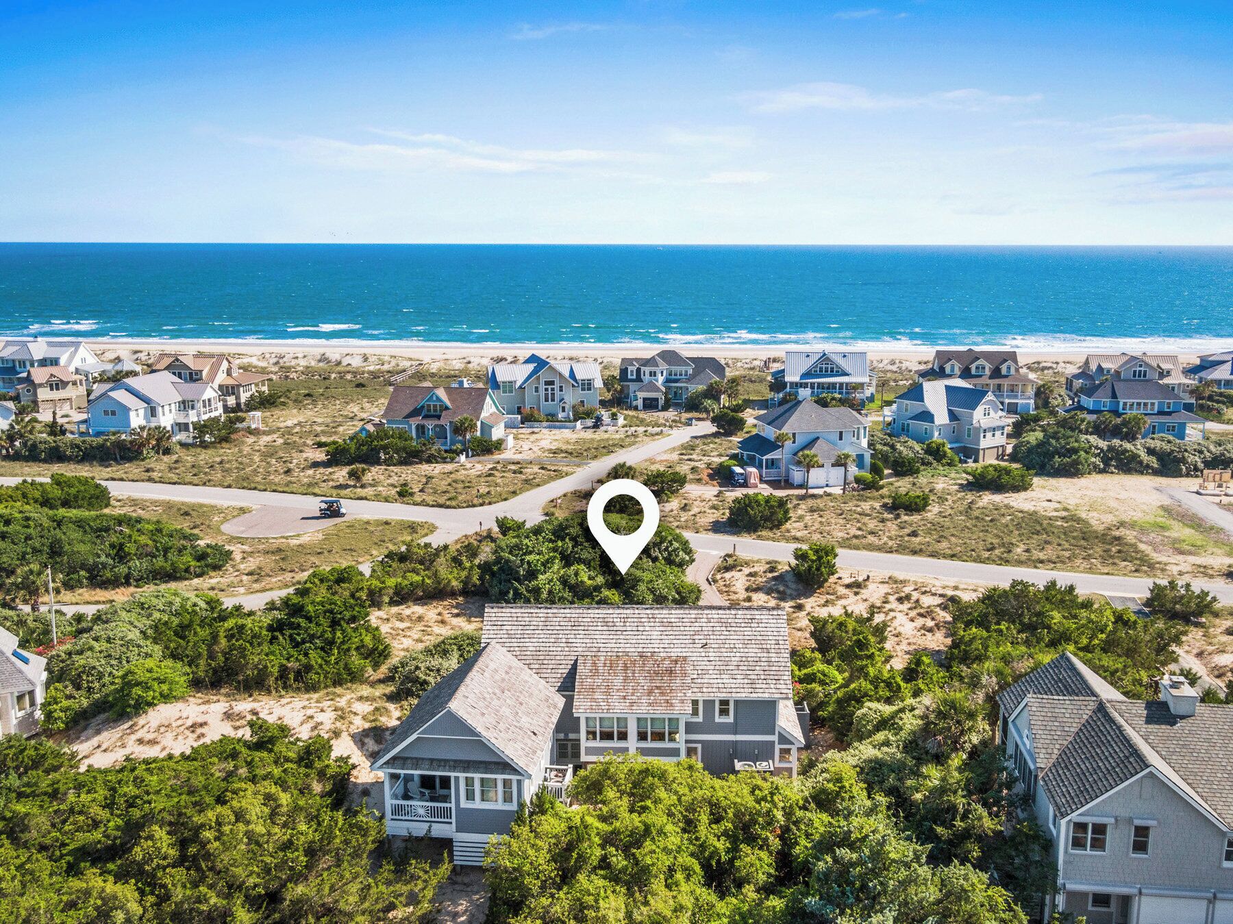 A coastal residential area with houses, a beach, and a clear sky.