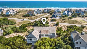 A coastal residential area with houses, a beach, and a clear sky.
