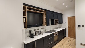 Une cuisine moderne avec des meubles de couleur sombre, un plan de travail blanc et des appareils électroménagers intégrés.