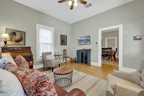 A living room with a sofa, armchair, coffee table, and a painting on the wall. - Austin Haus-Firepit-4Mins to Downtown (Fredericksburg)