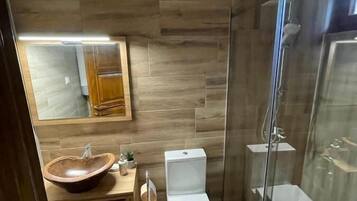 Un bagno moderno con una parete in legno, una cabina doccia in vetro e un water bianco.