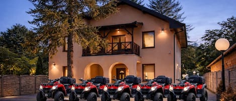 A building with a balcony and a driveway with ATVs parked in front.