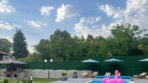 An outdoor swimming pool with lounge chairs and a pink flamingo float. - Casa Mia Vrdnik (Vrdnik)