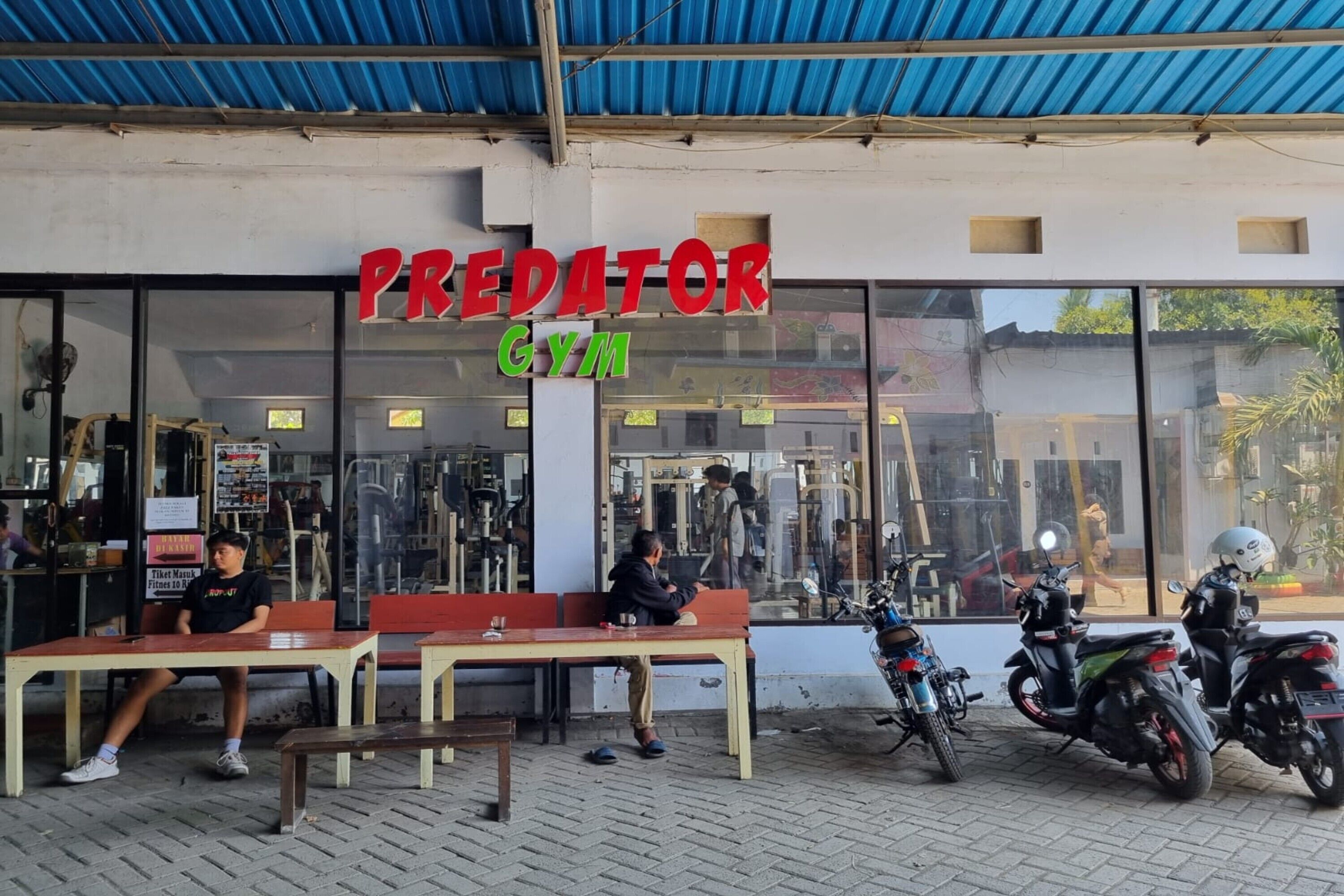 A gym named "Predator Gym" with a blue roof and large windows.