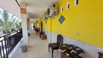 A corridor with yellow walls, air conditioning units, a trash bin, and a table with a placemat.