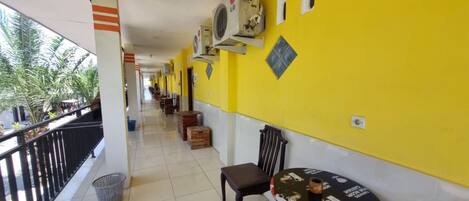 A corridor with yellow walls, air conditioning units, a trash bin, and a table with a placemat.
