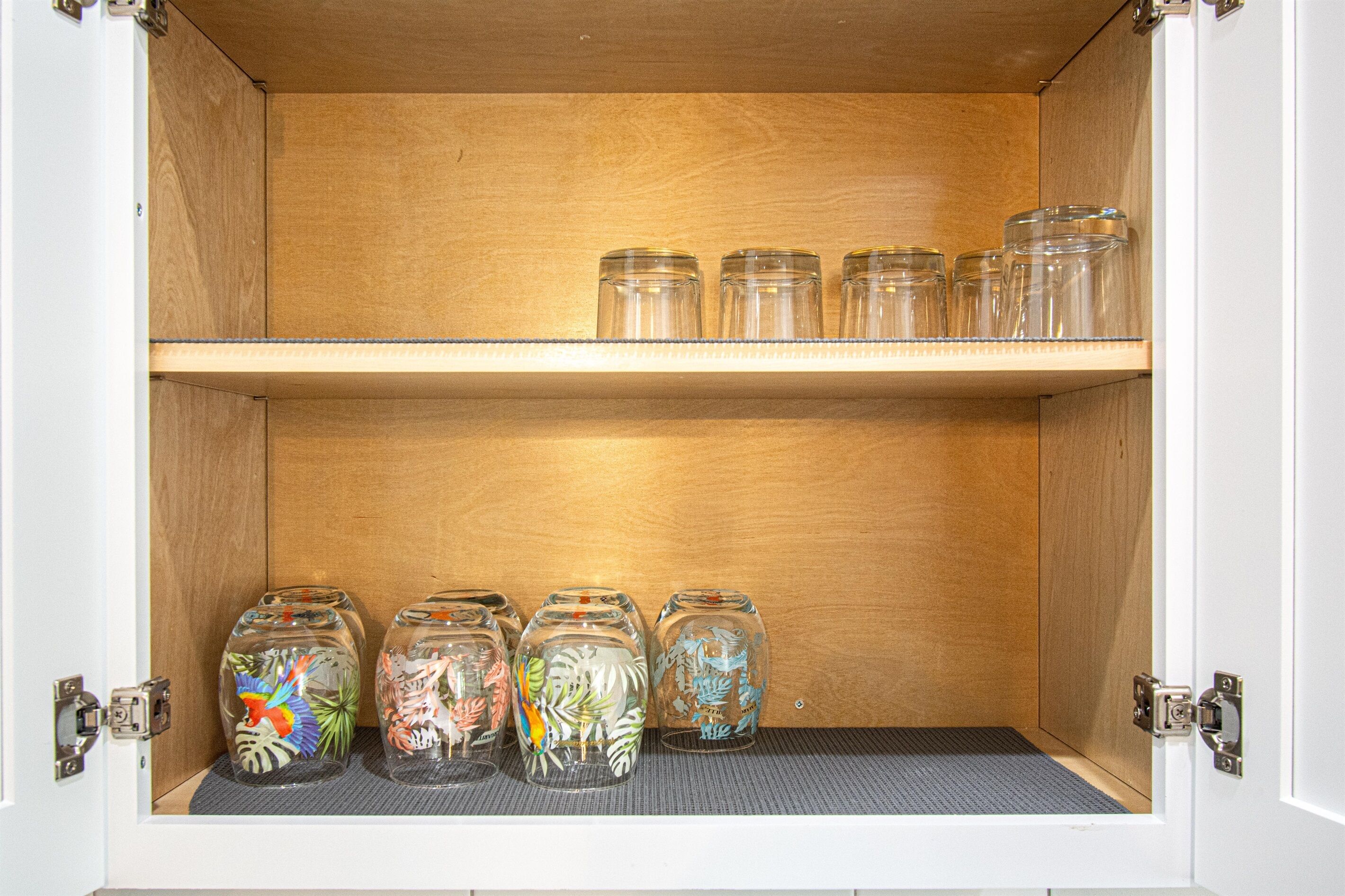 A wooden cabinet with two shelves, one holding clear glass jars and the other holding decorative glass jars with painted designs.