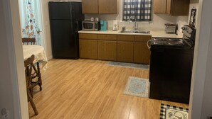 Una cocina con armarios de madera, un refrigerador negro, un microondas, una estufa y un lavabo.