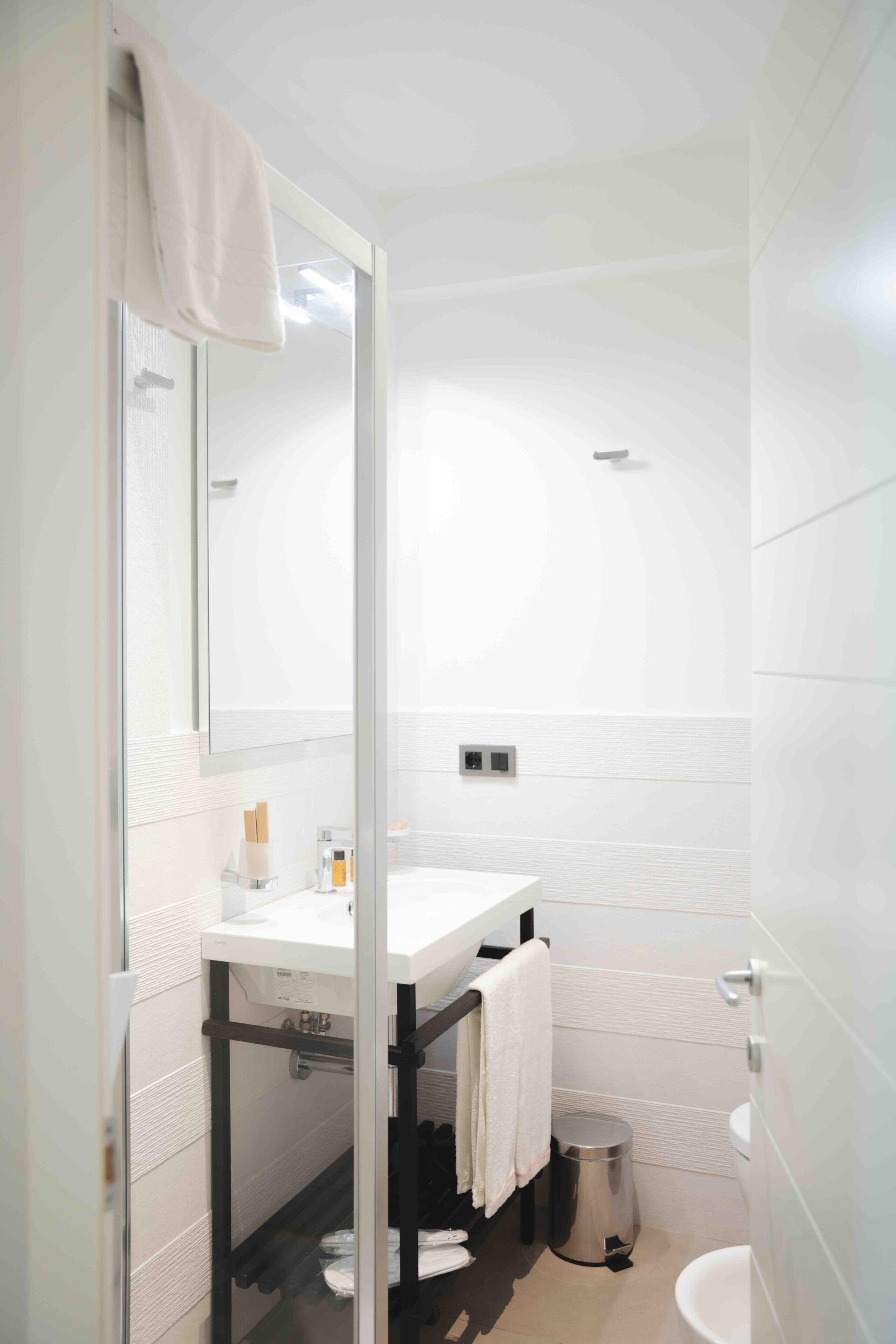 Un baño moderno con lavamanos, espejo y retrete blancos.